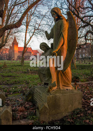 Soleil tôt le matin sur la statue sur une tombe dans un cimetière St Mary à Wandsworth, Londres Banque D'Images