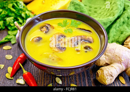 Purée de potiron avec soupe de champignons dans une tasse marron, vert serviette, persil, piment rouge gousses, graines de citrouille, le gingembre, la citrouille Banque D'Images