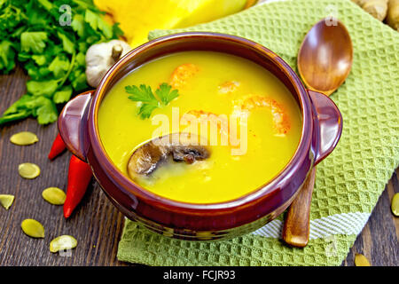 À soupe de potiron purée aux crevettes et champignons dans un bol d'argile avec une cuillère sur la serviette, la citrouille, le persil, le gingembre, le piment fort Banque D'Images