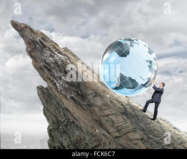 Young businessman rolling Earth planet up th hill Banque D'Images