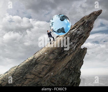 Young businessman rolling Earth planet up th hill Banque D'Images