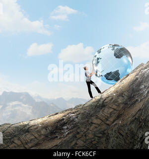 Young businesswoman rolling Earth planet up th hill Banque D'Images