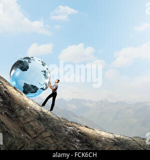 Young businesswoman rolling Earth planet up th hill Banque D'Images