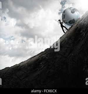 Young businesswoman rolling Earth planet up th hill Banque D'Images