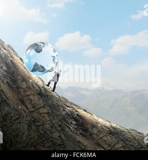 Young businessman rolling Earth planet up th hill Banque D'Images