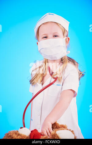 Petite fille habillé comme un médecin, une infirmière avec un stéthoscope, examinant un patient. Banque D'Images