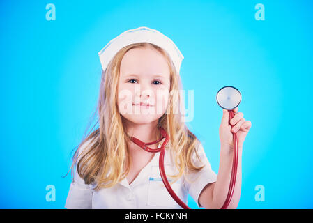 Petite fille habillé comme un médecin, une infirmière avec un stéthoscope, examinant un patient. Banque D'Images