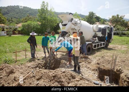 Les hommes birmans travaillant la coulée du béton pour un mur en Thaïlande Banque D'Images