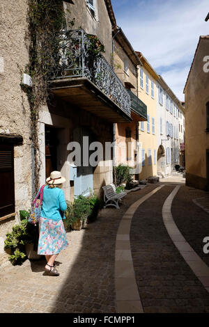 Femme marchant dans rue étroite dans pittoresque village perché, Mons-en-Provence dans le Var. Banque D'Images