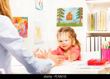 Petit bambin faisant des exercices de doigts à table Banque D'Images