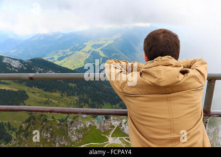 Jeune homme regarde la vue tout en étant assis sur la montagne Banque D'Images