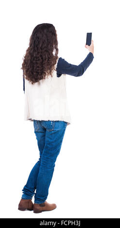 Vue arrière de l'article jeune femme belle et à l'aide d'un téléphone mobile. girl. Vue arrière Vue arrière. collection les gens de personne. Plus isolé sur fond blanc. Fille avec de longs cheveux bouclés photographié sur le téléphone. Banque D'Images