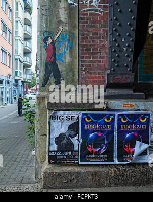 Garçon à l'aide d'un lance-pierres par artiste de rue, Alias. Street art et affiches sous un viaduc ferroviaire à Berlin Banque D'Images