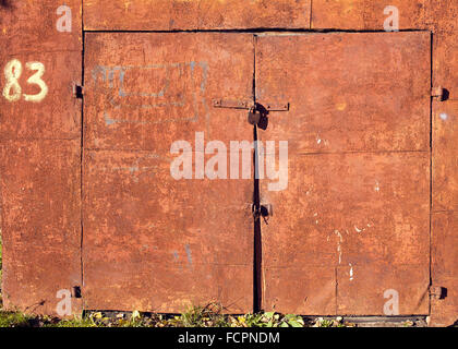 Rusty weathered rouge portes verrouillées par cadenas Banque D'Images