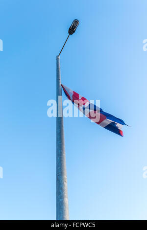 Déchiré en lambeaux un un Union Jack drapeau flotte à partir d'un lampadaire de Belfast. Banque D'Images