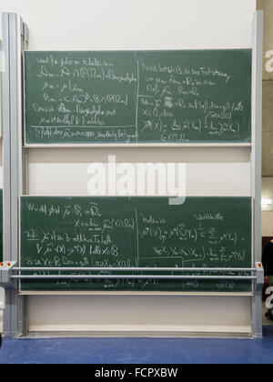 Formules mathématiques complexes écrit sur un grand tableau noir double à l'université. Banque D'Images