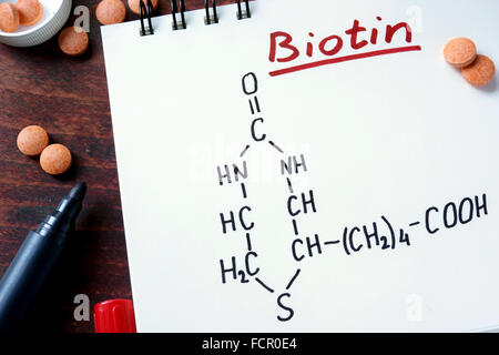 Le bloc-notes avec la biotine et pilules sur la table. Banque D'Images