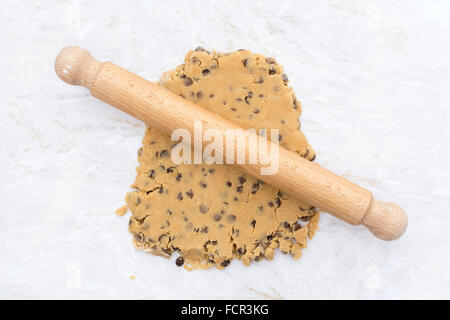 Le beurre d'arachide et la pâte à biscuits aux pépites de chocolat en cours de déploiement avec un rouleau à pâtisserie en bois Banque D'Images