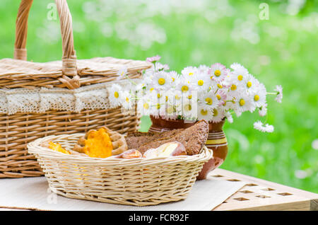 Petits pains dans un panier en osier et un bouquet de fleurs Banque D'Images