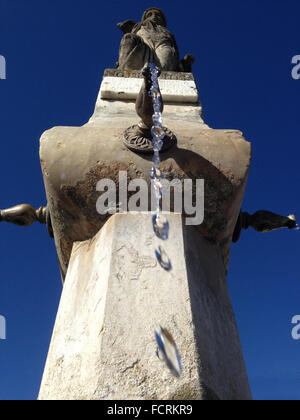 Close-up d'une vieille fontaine en pierre avec des gouttes d'eau et fond de ciel bleu. Low angle Banque D'Images