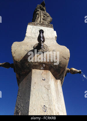 Close-up d'une vieille fontaine en pierre avec des gouttes d'eau et fond de ciel bleu. Low angle Banque D'Images