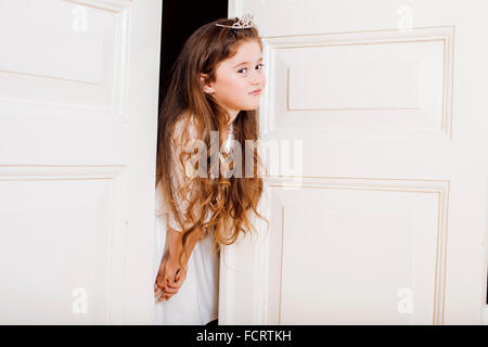 Peu jolie fille à la maison, de l'ouverture de la porte bien-habillé en robe blanche, adorable fée des dents de lait Banque D'Images