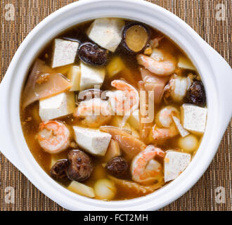 Angle de vue élevé soupe asiatique composé de crevettes, champignons, tofu, légumes et sur le tapis de bambou. Banque D'Images