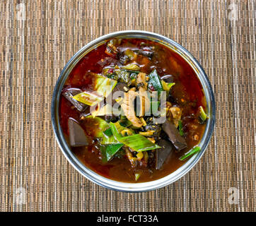 Angle de vue élevé une marmite remplie de légumes, sauce poivre épicé et le tofu soupe pour le dîner sur le tapis de bambou. Banque D'Images