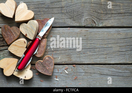 Coeurs en bois sculpté et le couteau de l'amour abstrait concept Banque D'Images