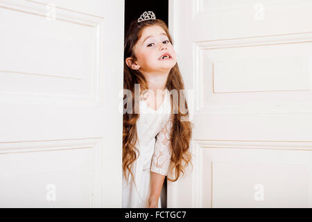 Peu jolie fille à la maison, de l'ouverture de la porte bien-habillé en robe blanche, adorable fée des dents de lait Banque D'Images