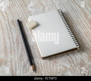 Photo de carnet vierge avec un crayon et une gomme sur fond en bois clair avec des ombres douces. Mock-up pour l'identité de marque. Banque D'Images