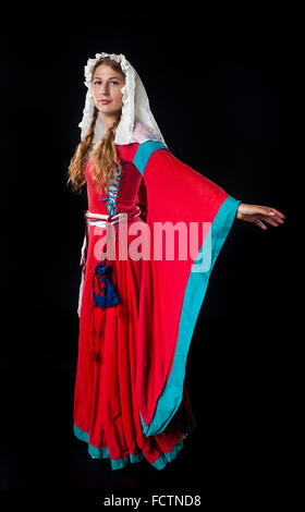 Portrait de jeune fille médiévale dans une robe rouge et foulard sur fond noir Banque D'Images