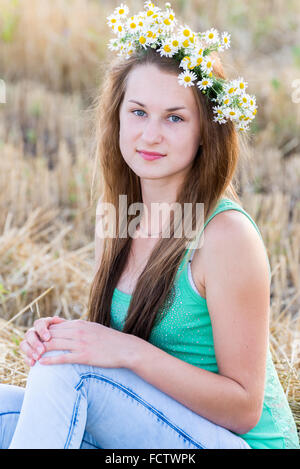 Teen girl avec une couronne de marguerites dans le champ Banque D'Images