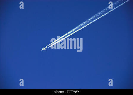 Un avion laisse une longue traînée dans le ciel bleu. Banque D'Images