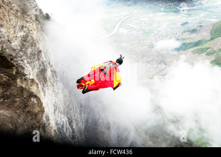 Ce cavalier BASE wingsuit juste quitté d'une falaise dans la vallée. Il va ouvrir son parachute juste avant de frapper le sol. Banque D'Images