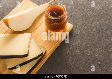 Une composition de tranches de fromage pecorino italien avec de la confiture et les poires sur une planche à découper en bois Banque D'Images