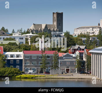 Des maisons par l'étang avec en arrière-plan l'église de Landakot, Reykjavik, Islande Banque D'Images