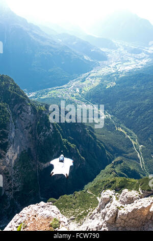 Ce cavalier BASE wingsuit juste quitté d'une falaise dans la vallée. Il va ouvrir son parachute juste avant de frapper le sol. Banque D'Images