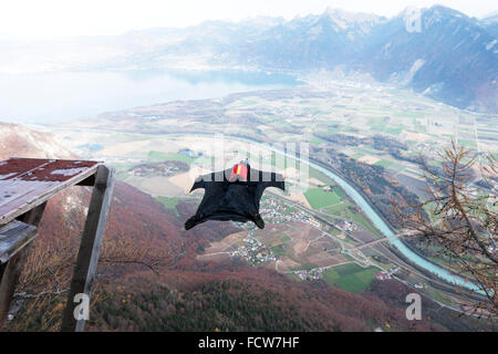 Ce cavalier BASE wingsuit juste sorti d'un tremplin vers le bas dans la vallée. Il va ouvrir son parachute juste avant le sol. Banque D'Images