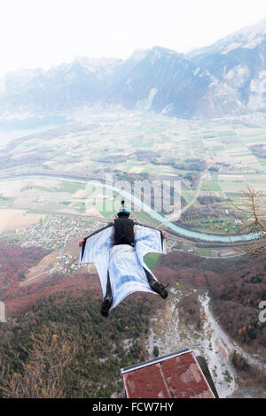 Ce cavalier BASE wingsuit juste sorti d'un tremplin vers le bas dans la vallée. Il va ouvrir son parachute juste avant le sol. Banque D'Images