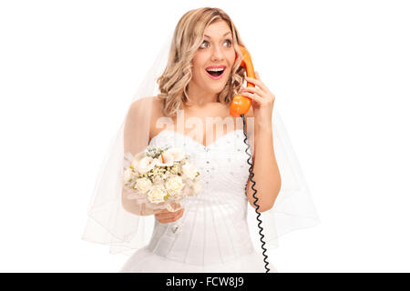 Cheerful bride holding a bouquet de mariage et de parler au téléphone isolé sur fond blanc Banque D'Images