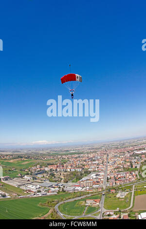 Cavalier est Parachute volant sous sa verrière sur une ville en Italie. Il est ainsi à la recherche de la zone d'atterrissage dédié vers le bas. Banque D'Images