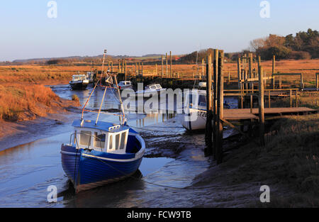 Des bateaux et des jetées de la marée basse à Thornham Harbour sur la côte nord du comté de Norfolk. Banque D'Images