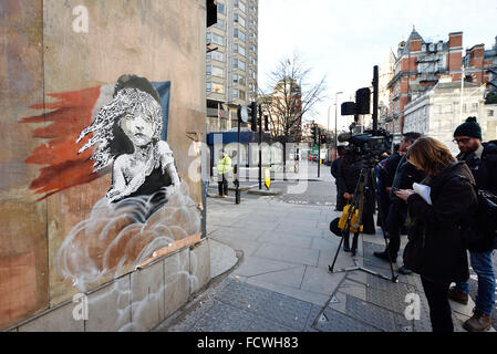 Londres, Royaume-Uni. 25 Jan, 2016. Ouvriers agissant à l'ordre du propriétaire du bien essayer d'enlever la nouvelle Art Banksy en face de l'Ambassade de France qui montre de Cosette ÒThe MiserablesÓ en réponse à l'utilisation récente de gaz lacrymogène dans le camp de réfugiés de la jungle de Calais situé en France. L'œuvre comprend un QR code qui renvoie à une vidéo montrant les réfugiés auraient été gazés lacrymogènes commencent. Credit : Raymond Tang/Alamy Live News Banque D'Images