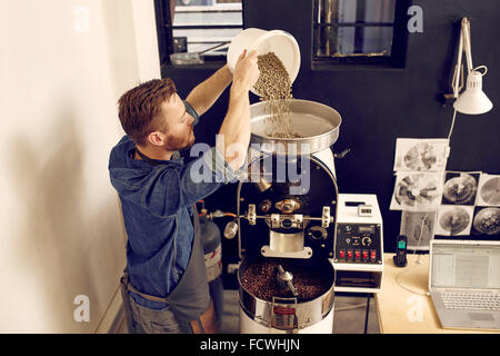 Man pouring matières grains de café dans une machine moderne Banque D'Images