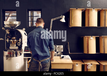 Homme travaillant dans sa torréfaction du café moderne avec un rangement Banque D'Images