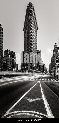 Flatiron Building en noir et blanc avec la voiture tout en légèreté sur la 5e Avenue, à la brunante à Midtown Manhattan, New York City Banque D'Images