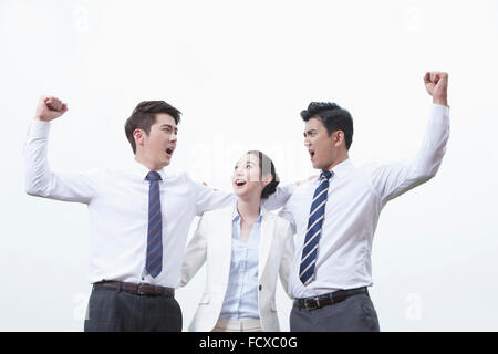 Low angle de deux hommes montrant l'énergie avec leurs poings et pompé avec leurs bras autour de l'autre avec une femme d'affaires Banque D'Images