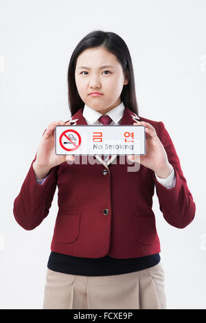 High school girl in school uniform holding aucun signe de fumer en fronçant face Banque D'Images