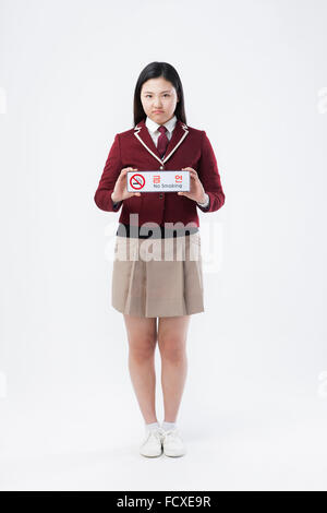 High school girl in school uniform holding aucun signe de fumer en fronçant face Banque D'Images